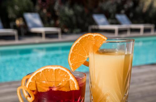 a drink and an orange slice on a table next to a pool at Le Lodge des Îles d'Or in Hyères