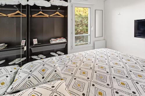 ein Schlafzimmer mit einem Bett mit Bettdecke und einem Fenster in der Unterkunft RÉSIDENCE ALCANTARA vue mer, première ligne in Saint-Brevin-les-Pins