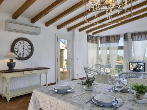 a dining room with a table and a clock on the wall at Case Li Conchi Sardegna in Castiadas