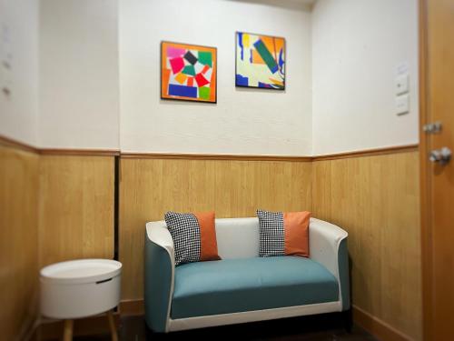 a waiting room with a blue couch and some paintings at 利園賓館 in Hong Kong