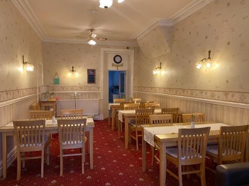 restauracja ze stołami i krzesłami oraz zegarem na ścianie w obiekcie The Laurels w Blackpool