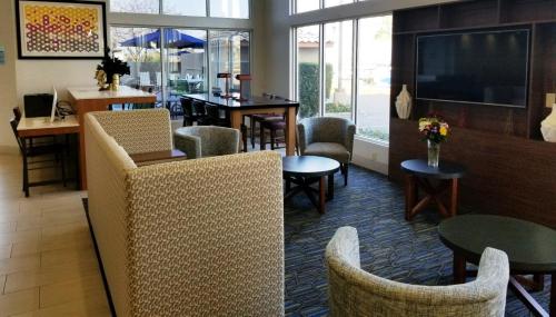 a restaurant with chairs and tables and a tv at Holiday Inn Express Madera by IHG in Madera