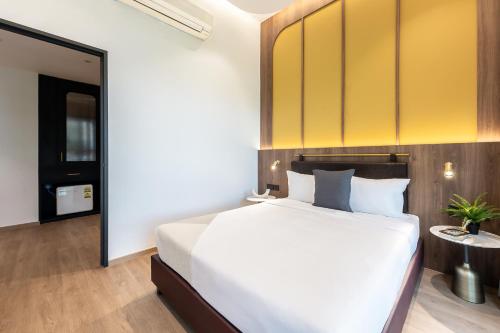 a bedroom with a white bed and a yellow wall at Owen House by Habyt in Singapore