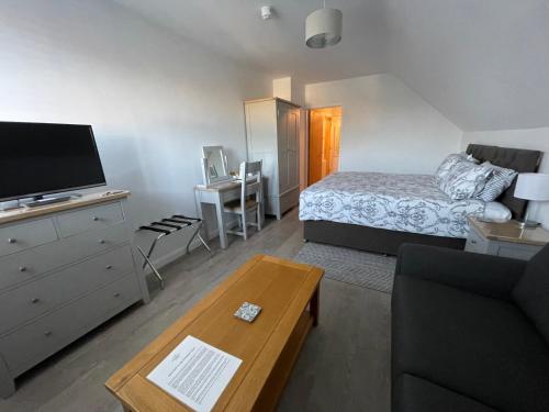 a living room with a bed and a tv and a couch at Cotswold Hare in Cirencester