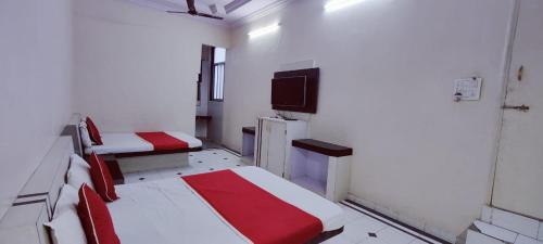 a room with three beds and a flat screen tv at Hotel Saideep Villas, Shirdi in Shirdi