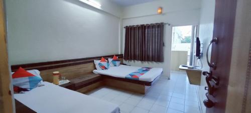 a hotel room with two beds and a window at Hotel Saideep Villas, Shirdi in Shirdi