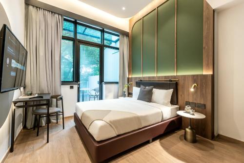 a hotel room with a bed and a desk and window at Owen House by Habyt in Singapore