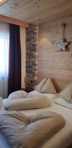 2 camas en una habitación con pared de madera en Hotel Azola, en Canazei
