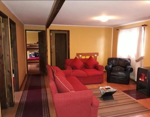 sala de estar con sofá rojo y silla en Hosteria y Cabañas Rucantu en Freire