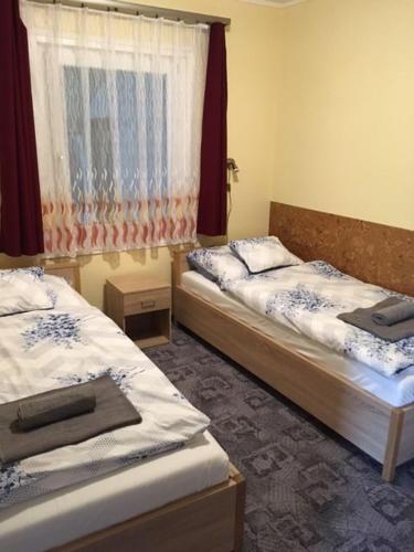 1 dormitorio con 2 camas y ventana en Százszorszép Vendégház, en Mezőkövesd