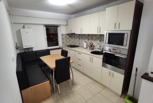 a kitchen with white cabinets and a table with chairs at Apartament - central in Târgu Jiu