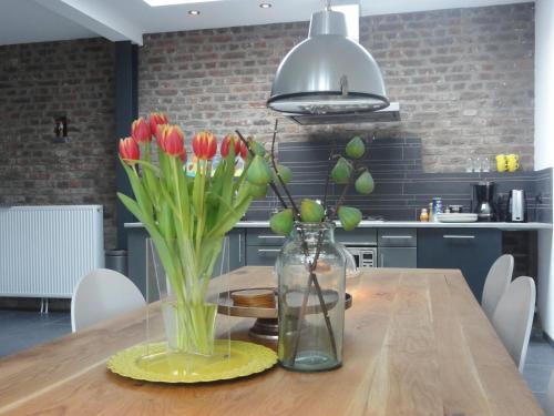 a wooden table with a vase of flowers on it at B&B Appartementen Engelenhof in Stevensweert