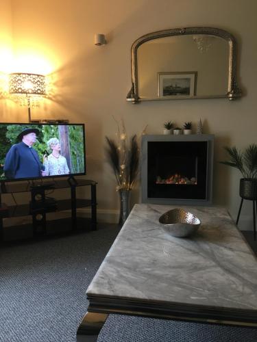 a living room with a fireplace and a tv at Silverhill House Apartment in Enniskillen