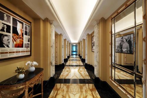 a hallway with yellow walls and a black and white tile floor at Hotel Imperial, a Luxury Collection Hotel, Vienna in Vienna