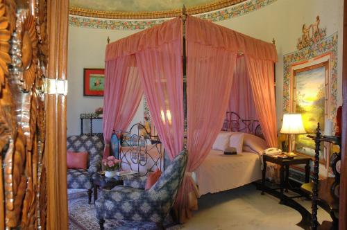 a bedroom with a canopy bed with two chairs at Shiv Niwas Palace by HRH Group of Hotels in Udaipur
