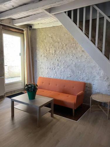 un salon avec un canapé orange et une table dans l'établissement Gite Le Baulois, maisonnette calme et confort en vallée de Loire, à Baule