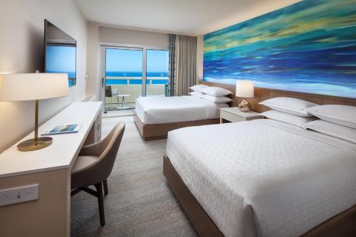 a hotel room with two beds and a large painting at Sheraton Waikiki Beach Resort in Honolulu