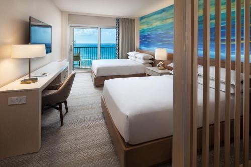 Sheraton Waikiki Beach Resort في هونولولو: غرفة في الفندق بسريرين ومكتب فيه مكتب
