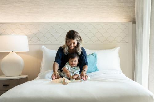 a woman holding a baby on a bed at Sheraton Waikiki Beach Resort in Honolulu