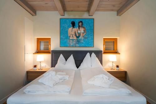 a bedroom with a large white bed with a painting on the wall at Stadl Niglberg Südsteiermark in Sankt Johann im Saggautal