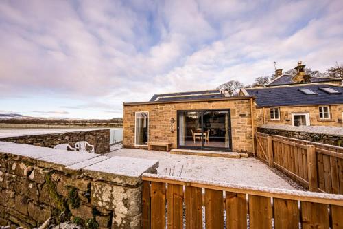 a brick house with a stone wall and a fence at Gardener's Cottage in Alnwick