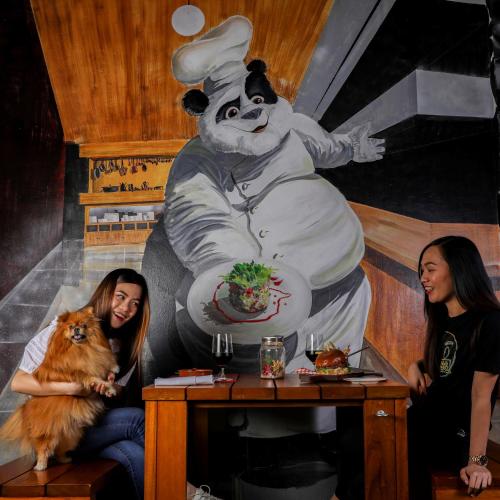 two women sitting at a table with a painting of a chef at Mövenpick Hotel Jumeirah Beach in Dubai