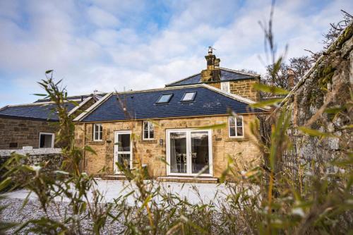 a stone house with a blue roof at The Kennelman 2 bedroom option in Alnwick