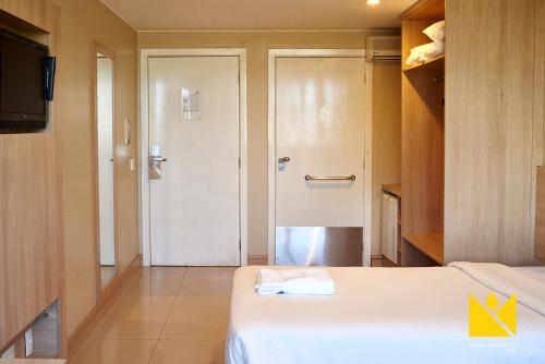 um quarto com duas camas e uma porta com televisão em Brasília Imperial Hotel e Eventos em Brasília
