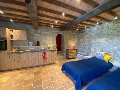 a bedroom with a blue bed and a kitchen at A l’ombre du Tilleul in Crestet