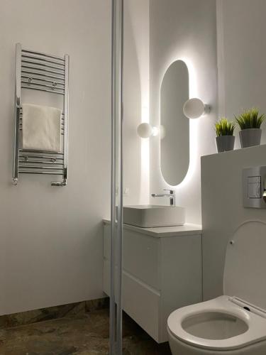 a white bathroom with a toilet and a mirror at RJ Family Sopot in Sopot