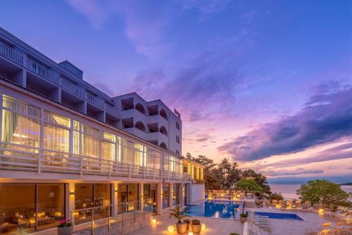 un hotel con piscina al anochecer en Hotel Malin en Malinska