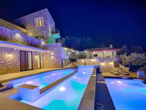 a swimming pool in front of a house at night at Sky Sea Resort & Villas in Skiathos Town