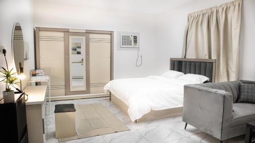 a bedroom with a bed and a chair and a couch at Comfortable & Big Family Apartments 10Mins Drive to Al-Masjid -Nabawi - Nozol Noor 2 in Al Madinah
