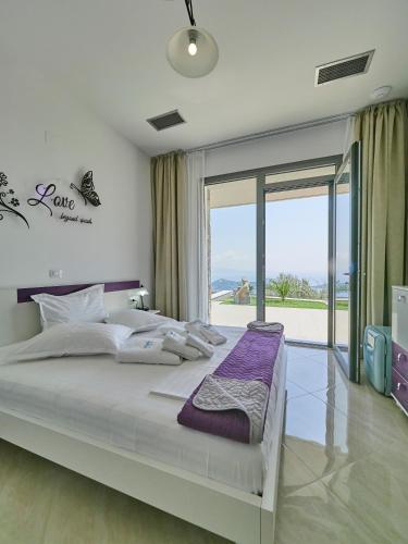 a bedroom with a large bed with a large window at Sky Sea Resort & Villas in Skiathos