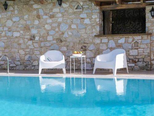 two chairs and a table next to a pool at Phoceus Poolfront Grande Villa in Palaiá Fókaia