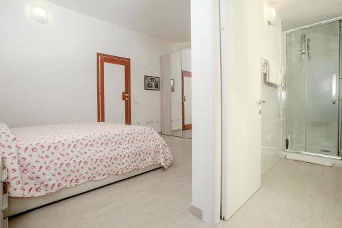 Dormitorio blanco con cama y ducha acristalada en Romeo and Juliet Affittacamere, en Santa Teresa Gallura