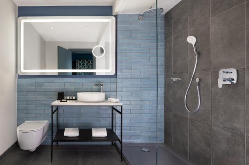 bagno con servizi igienici, lavandino e specchio di Sheraton Milan San Siro a Milano