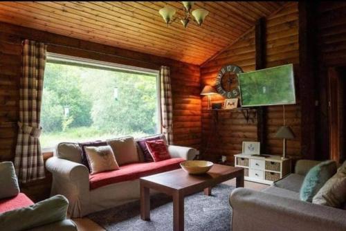 a living room with a couch and a large window at Grouse Lodge in Dunoon