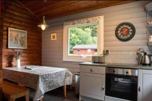 uma cozinha com uma mesa e uma mesa e uma janela em Grouse Lodge em Dunoon