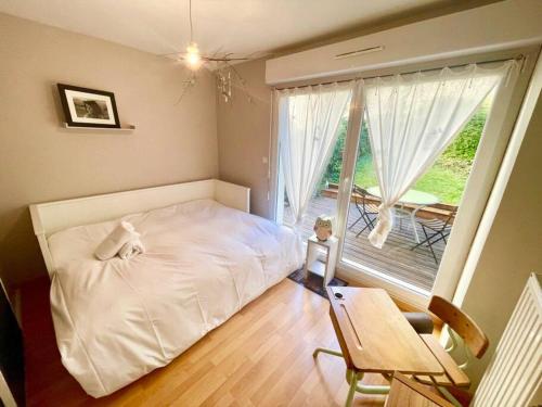 a bedroom with a white bed and a large window at Au nid de cigogne avec garage à Kaysersberg in Kaysersberg