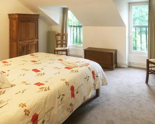 um quarto com uma cama, uma cadeira e uma janela em Le Moulin de Vaugien em Saint-Rémy-lès-Chevreuse