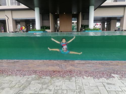 a young girl jumping into a swimming pool at Bali Residen, Mariam Indah Homestay Melaka in Melaka