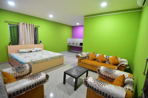 um quarto com paredes verdes e uma cama e cadeiras em Hira Panidihing Homestay em Sibsāgar