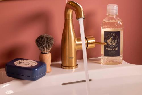 a sink with a faucet and a bottle of soap at Hôtel Jardin de Cluny in Paris