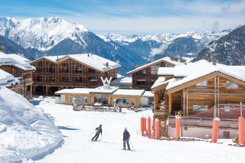 2 personnes skier dans la neige devant un lodge dans l'établissement W Verbier, à Verbier