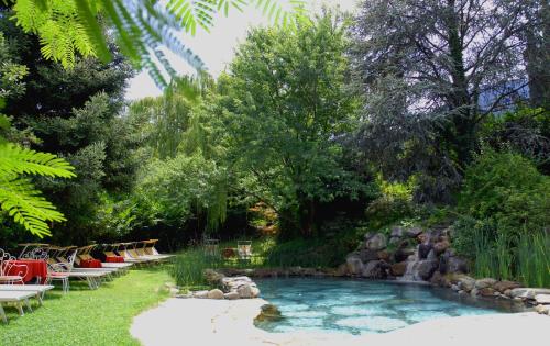 uma piscina num quintal com cadeiras e árvores em Hotel Braunsbergerhof em Lana