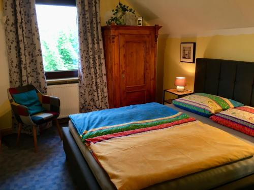 a bedroom with a bed and a chair and a window at AUSZEIT für DICH in Himmelkron