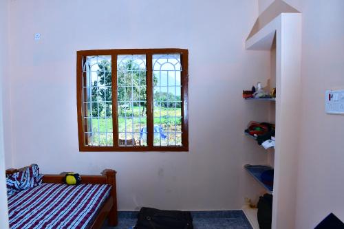 Habitación con cama y ventana en Tiru Arunachala Farm House, en Tiruvannāmalai