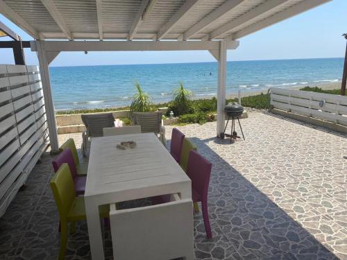 a white table and chairs on a patio with the beach at Seafront Beach House in Meneou