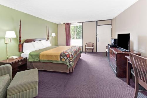 a hotel room with a bed and a television at Super Inn & Suites Carrollton in Carrollton